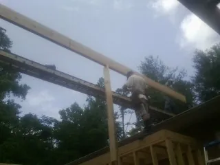Carpenter setting a ridge beam over a new addition frame — Ice Dam Removal by Roofing Brothers in Fort Lupton