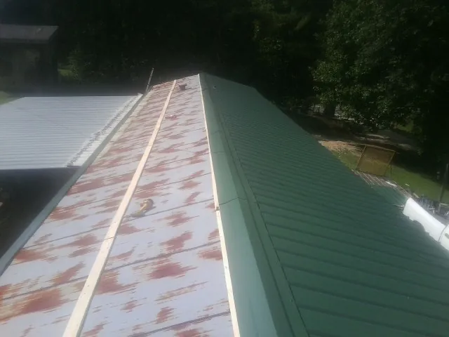 Old rusted panels beside newly installed green metal roofing — Wind Damage Roof Repair by Roofing Brothers in Fort Lupton