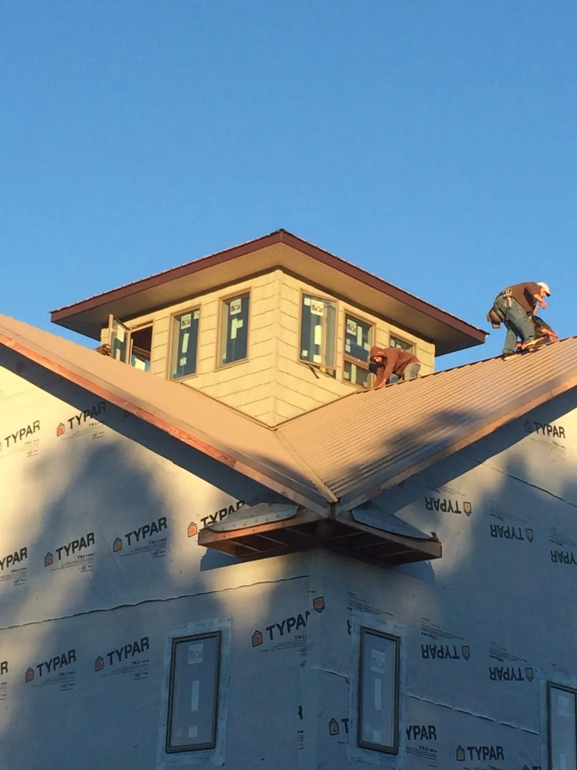 Roofers working around a rooftop cupola on a new metal roof at sunset — Roof Waterproofing in Fort Lupton by Roofing Brothers